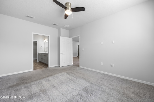 unfurnished bedroom with light carpet, connected bathroom, a textured ceiling, and ceiling fan