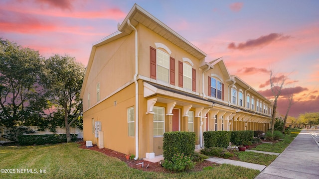 property exterior at dusk with a lawn