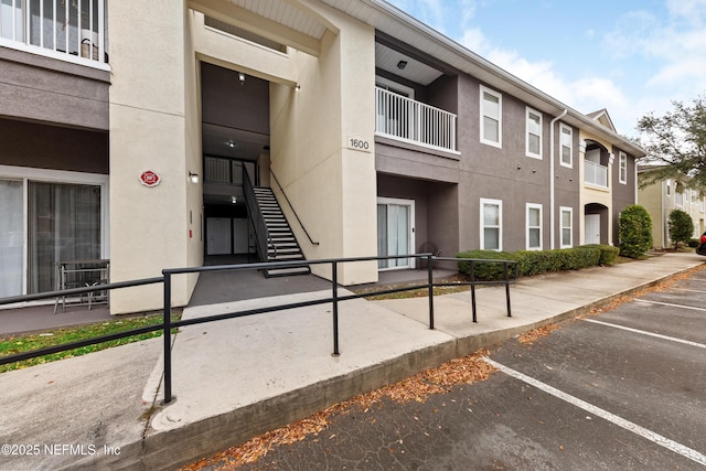 view of building exterior featuring stairs and uncovered parking