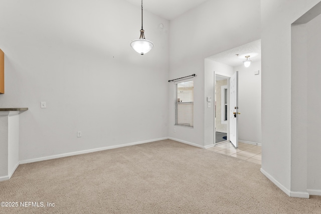 interior space featuring carpet floors, a high ceiling, tile patterned flooring, and baseboards