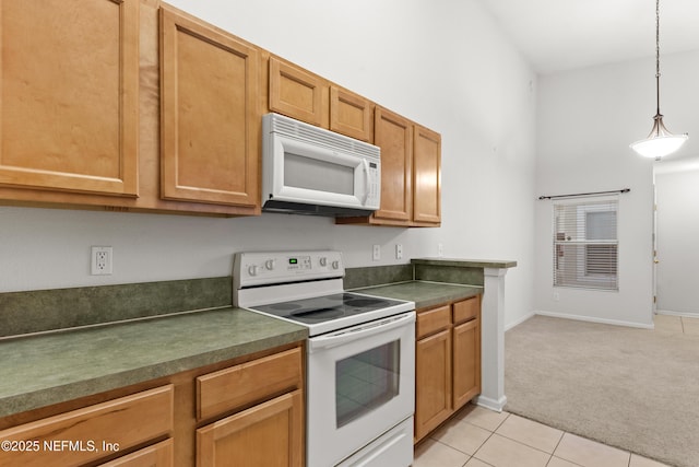 kitchen with light tile patterned floors, light carpet, white appliances, hanging light fixtures, and dark countertops