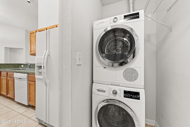 laundry room featuring light tile patterned floors, stacked washer / drying machine, and sink