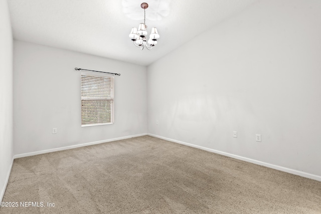 spare room with carpet flooring and a notable chandelier