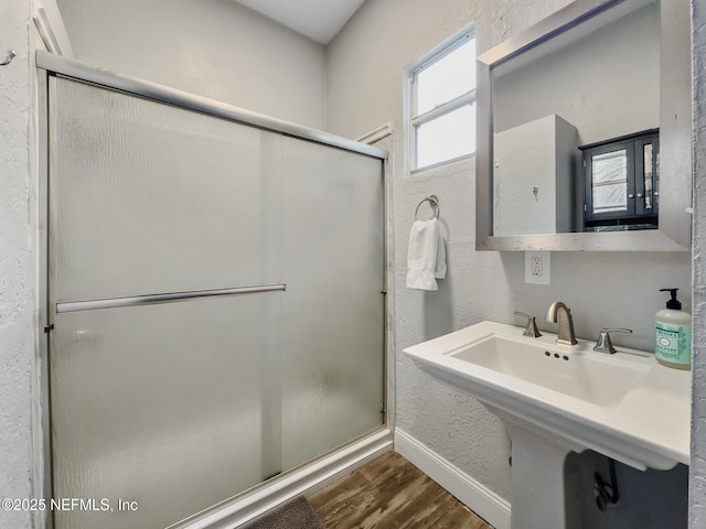 bathroom with hardwood / wood-style floors, a shower with door, and sink