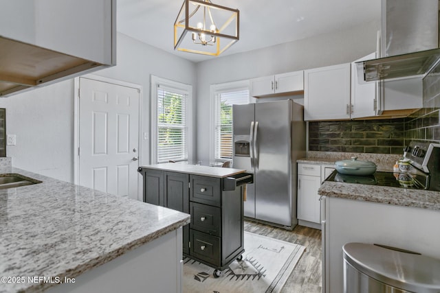 kitchen featuring backsplash, stainless steel appliances, decorative light fixtures, white cabinetry, and range hood