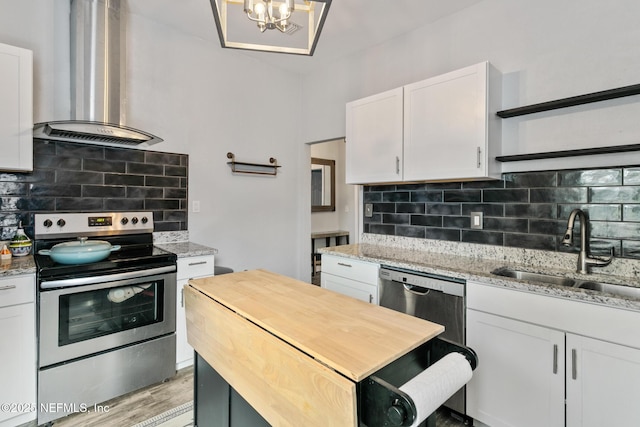 kitchen featuring white cabinets, appliances with stainless steel finishes, sink, and wall chimney range hood