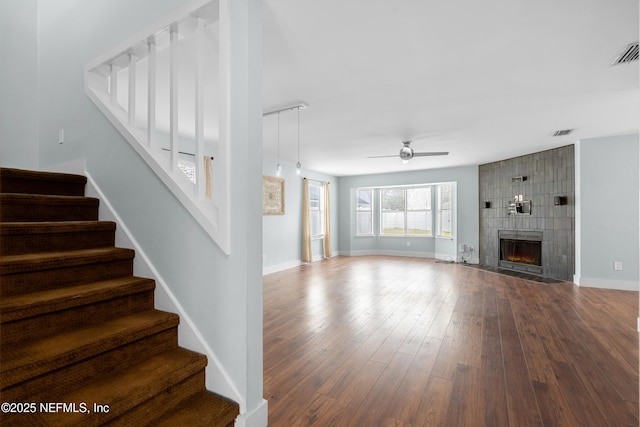 unfurnished living room featuring a tiled fireplace, hardwood / wood-style flooring, and ceiling fan