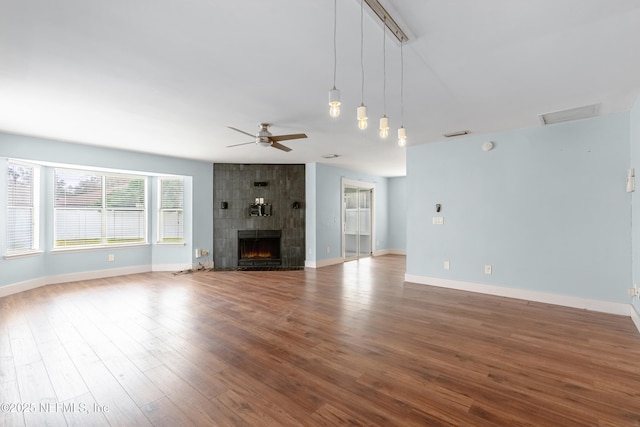 unfurnished living room featuring hardwood / wood-style flooring, a tile fireplace, and ceiling fan