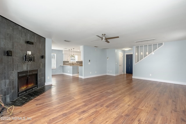 living room with a tiled fireplace, hardwood / wood-style flooring, and ceiling fan