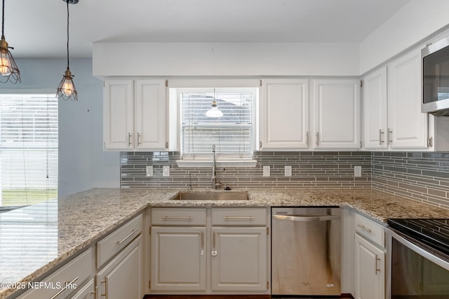 kitchen with decorative light fixtures, sink, white cabinets, decorative backsplash, and stainless steel appliances