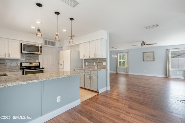 kitchen with a wealth of natural light, stainless steel appliances, light hardwood / wood-style floors, and white cabinets