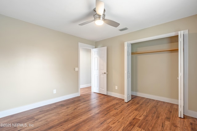 unfurnished bedroom with ceiling fan, wood-type flooring, and a closet