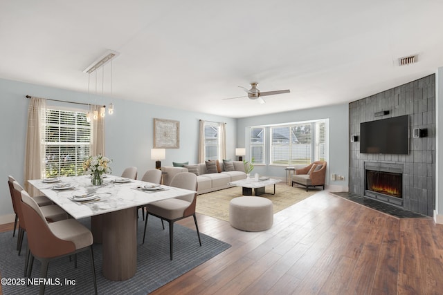 living room with hardwood / wood-style flooring, a large fireplace, and ceiling fan