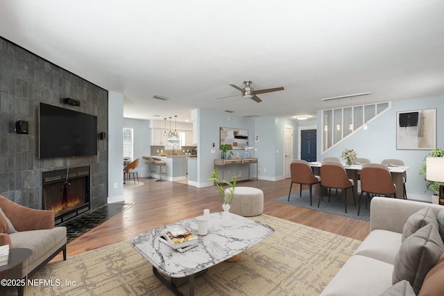 living room with ceiling fan, light wood-type flooring, and a fireplace