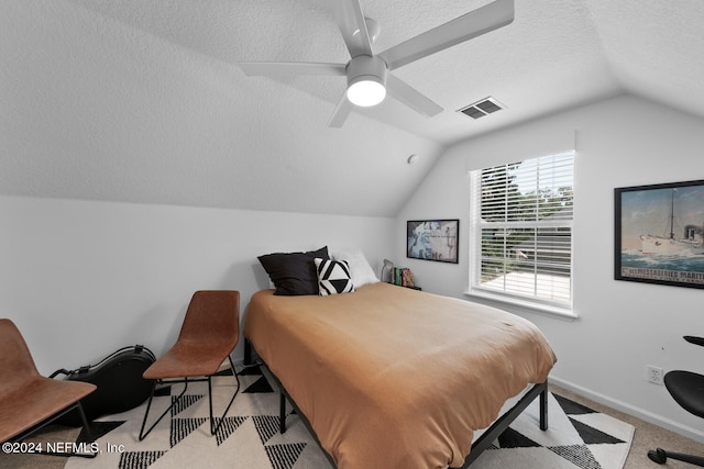 bedroom with ceiling fan, light colored carpet, lofted ceiling, and a textured ceiling