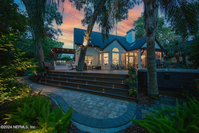 back house at dusk featuring a pergola and a patio area