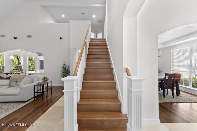 staircase with sink, a towering ceiling, and hardwood / wood-style flooring