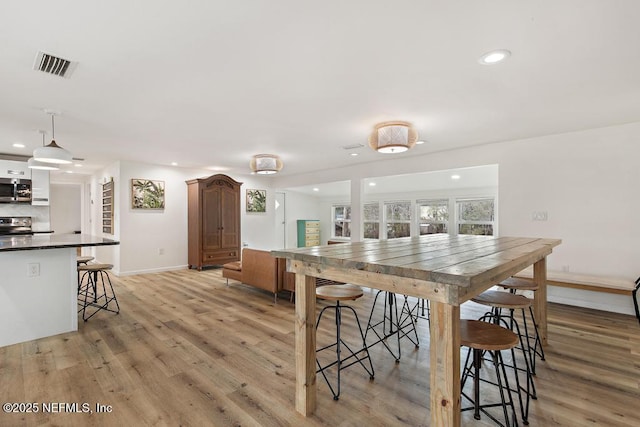 kitchen with a kitchen breakfast bar, light hardwood / wood-style floors, and pendant lighting