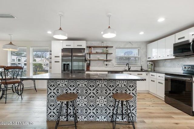 kitchen featuring sink, white cabinets, hanging light fixtures, and stainless steel appliances