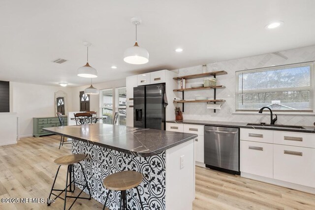 kitchen featuring pendant lighting, white cabinets, appliances with stainless steel finishes, sink, and a breakfast bar