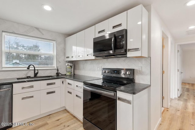 kitchen featuring sink, white cabinetry, light hardwood / wood-style flooring, and appliances with stainless steel finishes