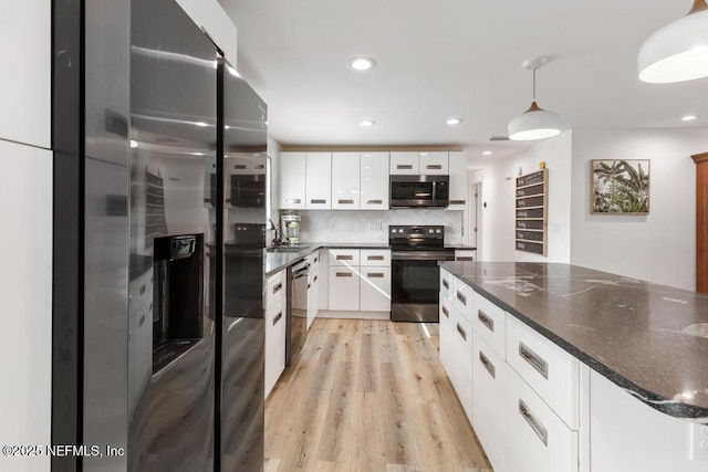 kitchen featuring appliances with stainless steel finishes, decorative light fixtures, white cabinetry, light hardwood / wood-style floors, and decorative backsplash