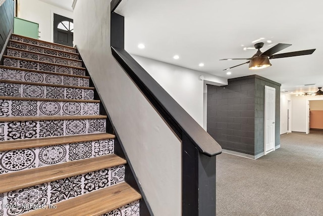 stairway with ceiling fan and carpet