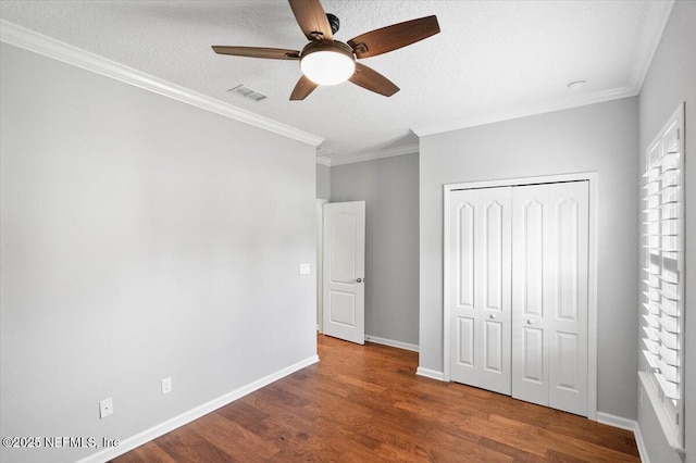 unfurnished bedroom with a textured ceiling, ceiling fan, multiple windows, and a closet