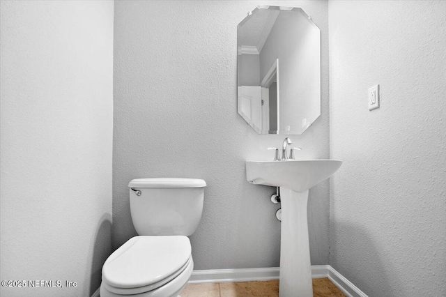 bathroom featuring tile patterned floors, toilet, and crown molding