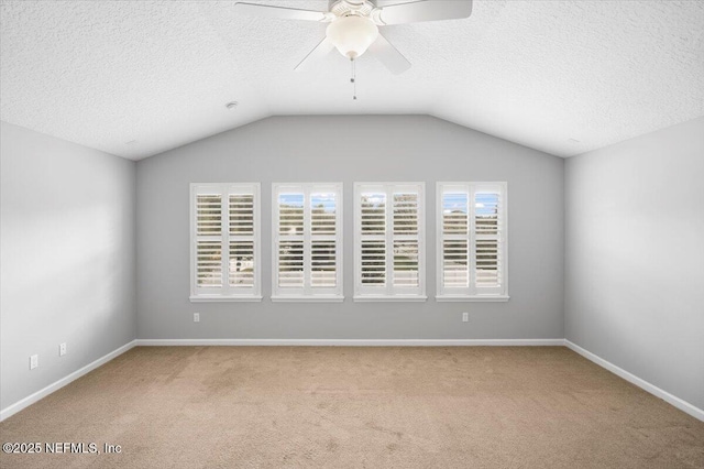 carpeted spare room with ceiling fan, a textured ceiling, and vaulted ceiling