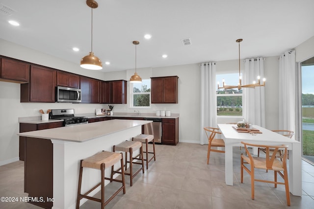 kitchen featuring sink, a center island, stainless steel appliances, pendant lighting, and a breakfast bar area