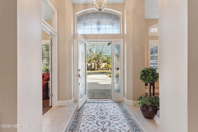 entryway with a high ceiling, light tile patterned floors, and a notable chandelier