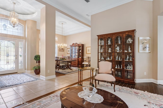 entryway featuring hardwood / wood-style flooring, ornamental molding, and an inviting chandelier