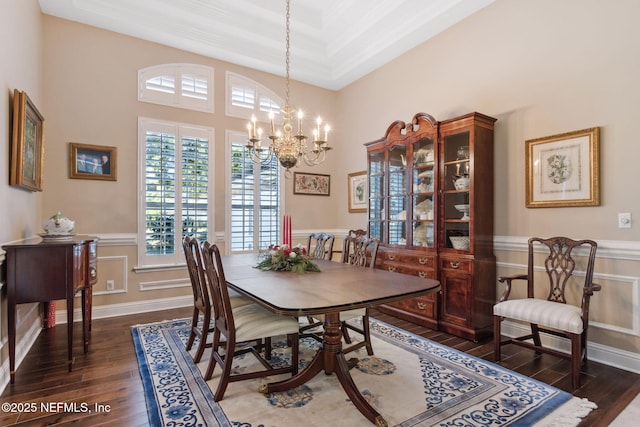 dining room featuring crown molding, dark hardwood / wood-style floors, a raised ceiling, and a notable chandelier