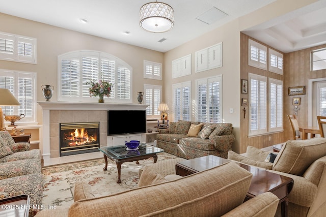 living room featuring plenty of natural light, a tile fireplace, and wooden walls