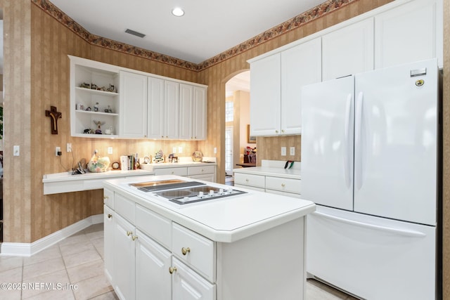 kitchen with white fridge, a kitchen island, white cabinetry, light tile patterned floors, and electric stovetop