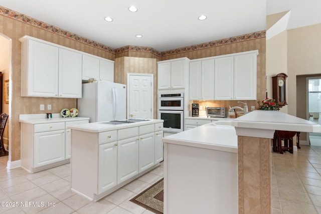 kitchen with white appliances, a kitchen island, white cabinetry, sink, and kitchen peninsula