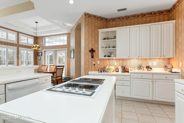 kitchen featuring white cabinetry, a tray ceiling, dishwasher, stovetop, and pendant lighting