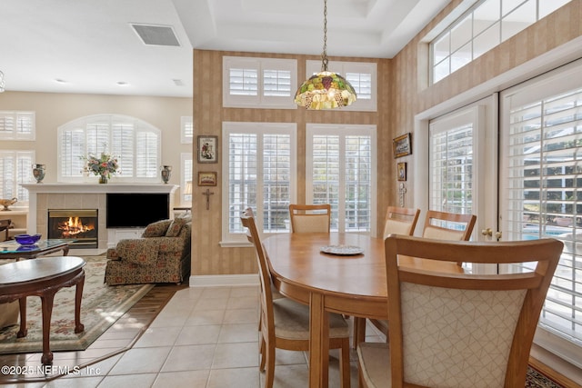 dining space with light tile patterned floors, a tiled fireplace, and a healthy amount of sunlight