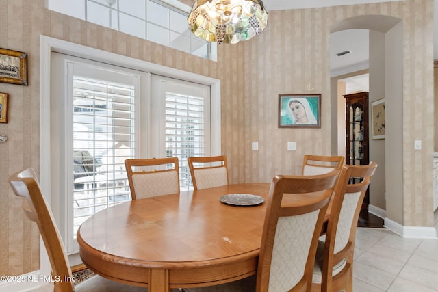 dining room with ornamental molding, a notable chandelier, and light tile patterned flooring