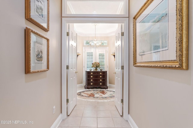 corridor featuring light tile patterned floors, ornamental molding, and a notable chandelier