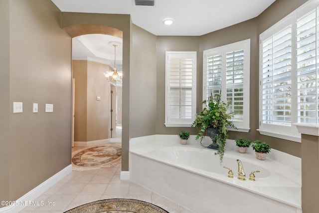 bathroom with tile patterned floors, a bathing tub, and a notable chandelier