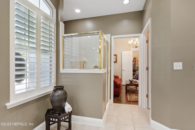 corridor featuring light tile patterned floors and a chandelier