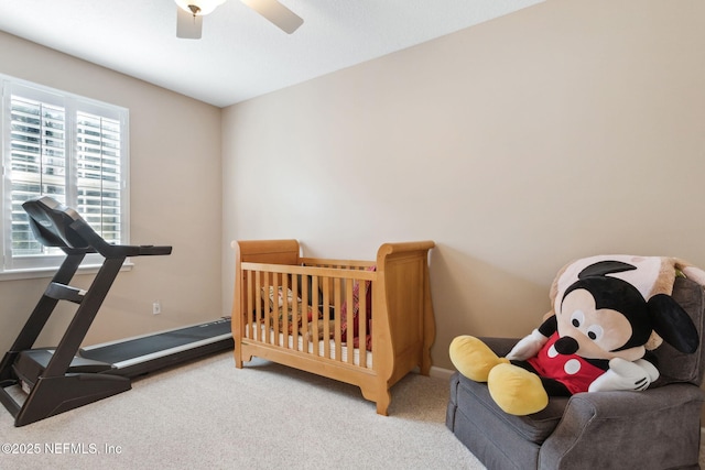 carpeted bedroom featuring ceiling fan and a nursery area