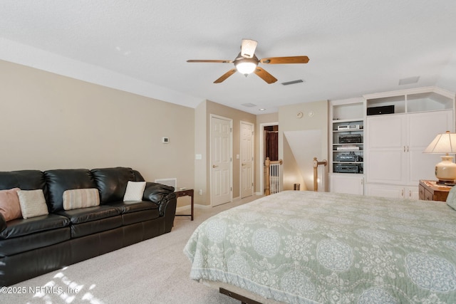 bedroom featuring light carpet, ceiling fan, and two closets