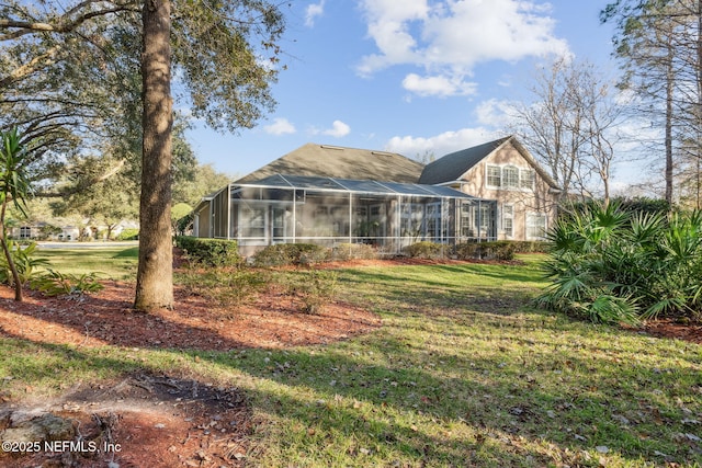 rear view of property with a lanai and a yard