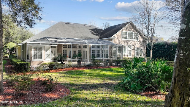 rear view of property with glass enclosure and a lawn