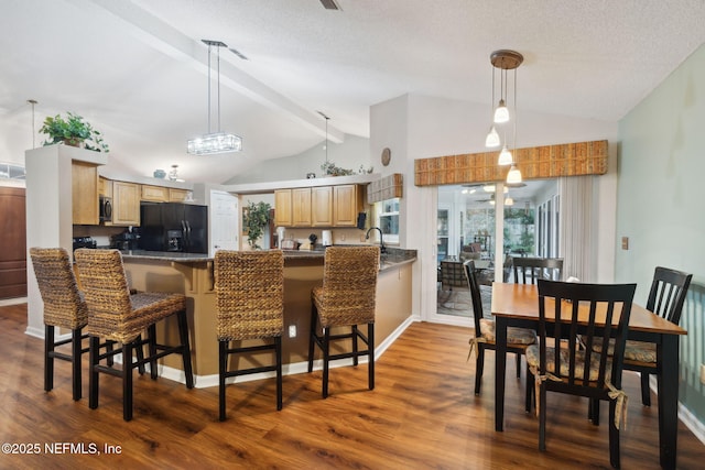 kitchen featuring black fridge, backsplash, kitchen peninsula, and a kitchen breakfast bar