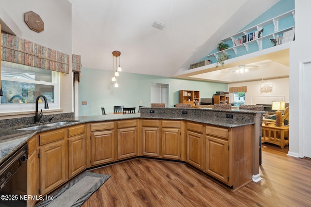 kitchen featuring hardwood / wood-style flooring, kitchen peninsula, dishwasher, vaulted ceiling, and sink