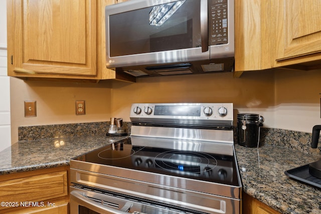 kitchen with appliances with stainless steel finishes and dark stone counters